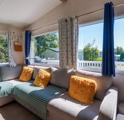 A living room with a sofa and large windows at Porthcurno 5 Perranwell near Goonhavern