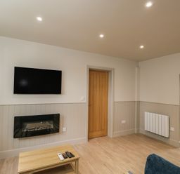A living room with a television above a fireplace and a coffee table at Foxglove in Stratton Audley near Bicester