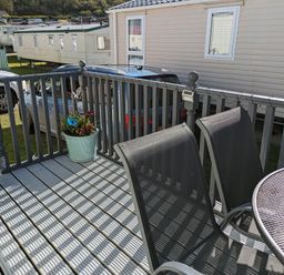 An outdoor deck with a table and chairs at Clarach Bay Holiday Village W18 Aberystwyth