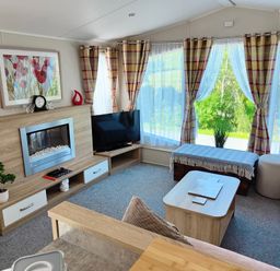 A living room with a fireplace and television at Clarach Bay Holiday Village W18 Aberystwyth