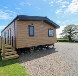 A mobile home with steps and grassy area at Sandpiper in Narberth