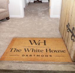 A hallway with a door mat and a couch at The White House Okehampton