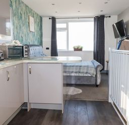 A kitchen with modern appliances and a bed at Two Bed Apartment No.4 in Newquay