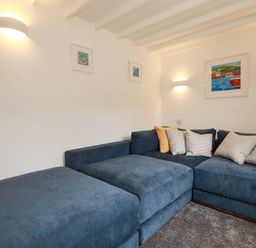 A living room with a sofa and wall art at Little House in Wadebridge