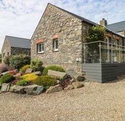 An outdoor view of stone houses and a landscaped garden at The Old Dairy near Solva