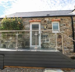An entrance with a glass railing and stone wall at The Old Dairy near Solva