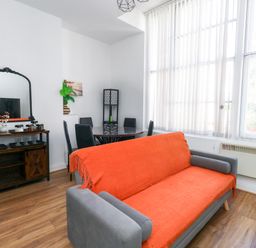 A living room with a sofa and a dining table at Ocean Breeze in Weymouth