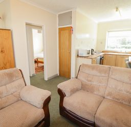 A living room with a sofa and kitchen area at Cottage 3 Tenby