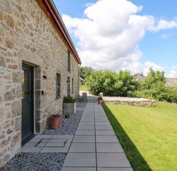 An outdoor area with a stone wall and pathway at Reddaway Byre Okehampton