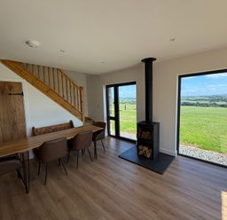 A dining room with a wood stove and large windows at High View Barn in Launceston