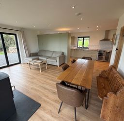 A living room with a dining table and kitchen area at High View Barn in Launceston