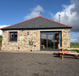 A stone building with a table and benches at High View Barn Launceston
