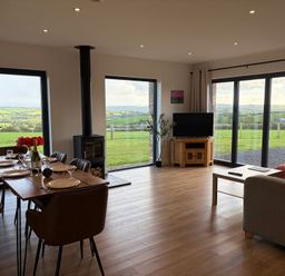 A living room with a dining area and large windows at High View Barn Launceston
