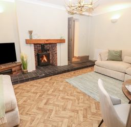 A living room with a fireplace and sofa at Corner House in Wark