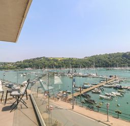 An outdoor balcony with chairs overlooking a marina at 5 Sails in Dartmouth
