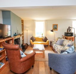 A living room with a sofa, television, and coffee table at Scoops’ Nook in Caernarfon