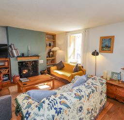 A living room with a sofa, television, and fireplace at Scoops’ Nook in Caernarfon