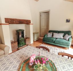 A living room with a fireplace wood stove and seating at The Coach House Cottage BALLYCOMMON