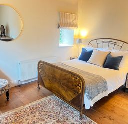A bedroom with a bed, bedside tables, and a chair at The Coach House Cottage in Ballycommon