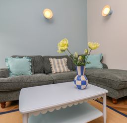 A living room with a sofa and vase of flowers at Apartment Blue in Whitby