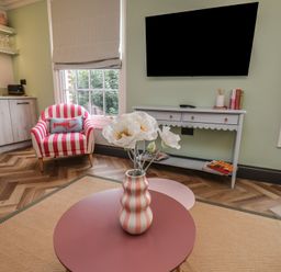 A living room with a striped chair, table, and flower vase at Apartment Green in Whitby