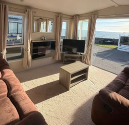 A living room with a television and coffee table at Trecco Bay holiday park, Porthcawl