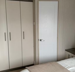 A bedroom with a wardrobe and a bed at Trecco Bay holiday park, Porthcawl