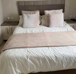 A bed with pillows and a bedside table at Trecco Bay holiday park, Porthcawl