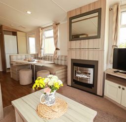 A living room with a table and chairs, television, and fireplace at Roslenn in St Agnes