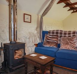 A living room with a blue armchair and a wood stove at Moorland Retreat in Bodmin