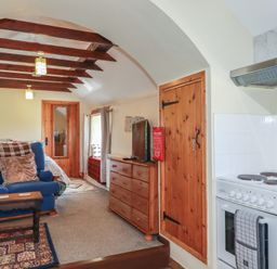 A living room with a sofa and kitchen area at Moorland Retreat in Bodmin