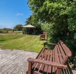 A garden with benches and table under a canopy at Moorland Retreat in Bodmin