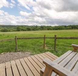 An outdoor area with wooden decking and a grassy field at The Little Shepherds Hut with a View Builth Wells