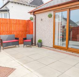 An outdoor area with seating and a sliding door at Smithy Cottage in Cemaes Bay