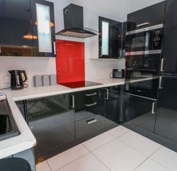 A kitchen with black cabinets and appliances at Smithy Cottage in Cemaes Bay