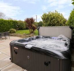 A garden with a hot tub and outdoor seating at Gwelfor in Cemaes Bay