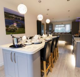 A kitchen with bar stools and dining table at Gwelfor in Cemaes Bay