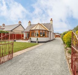 A house with a gravel driveway and a conservatory at Trefin Cemaes Bay