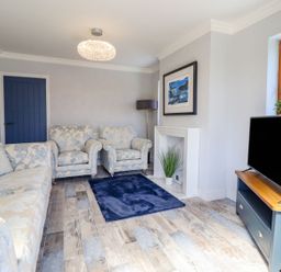 A living room with sofas and a television at Trefin Cemaes Bay