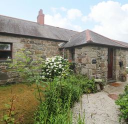 An outdoor view of a stone cottage entrance with garden at Swallow Cottage in Helston