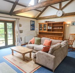 A living room with a sofa and coffee table at Swallow Cottage in Helston