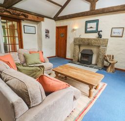 A living room with a sofa and coffee table at Swallow Cottage in Helston