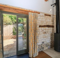 A living room with a wood stove and double doors at Frome Gazey in Frampton