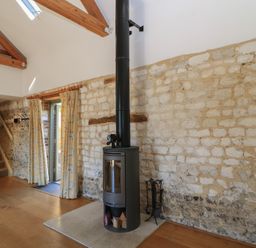 A living room with a wood stove and stone walls at Frome Gazey in Frampton