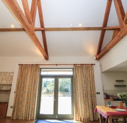 A dining room with wooden beams and sliding doors at Frome Gazey in Frampton
