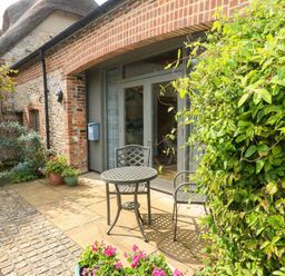 An outdoor seating area with a table and chairs at Frome Gazey Barn in Frampton