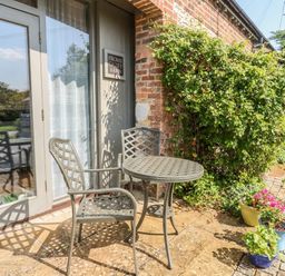 An outdoor seating area with a table and chairs at Frome Gazey Barn in Frampton