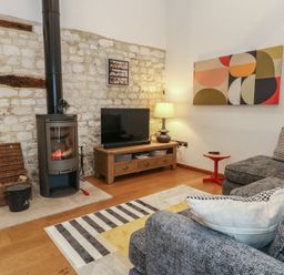 A living room with a television and stove at Frome Gazey Barn in Frampton