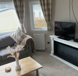A living room with a sofa, coffee table, and television at the property in an unspecified location