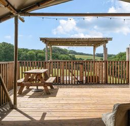 A deck with a wooden table and benches overlooking a landscape at Luxury Safari Lodge Sleeps 4/6 Deer Park Dogs Ok Zeal Monachorum near Bow